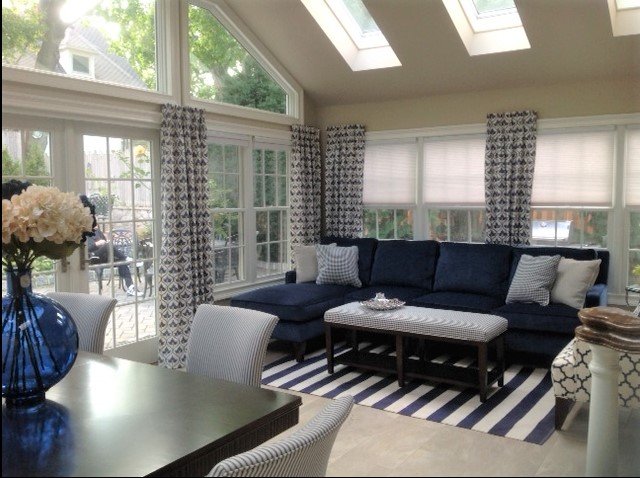 Sunroom with walls of windows, skylights a blue couch and coffee table and a dining table