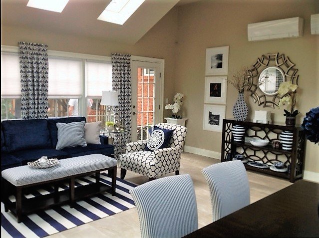 ALX Interiors Living area with a blue couch and blue and white striped rug with windows, a chair and tables and chairs
