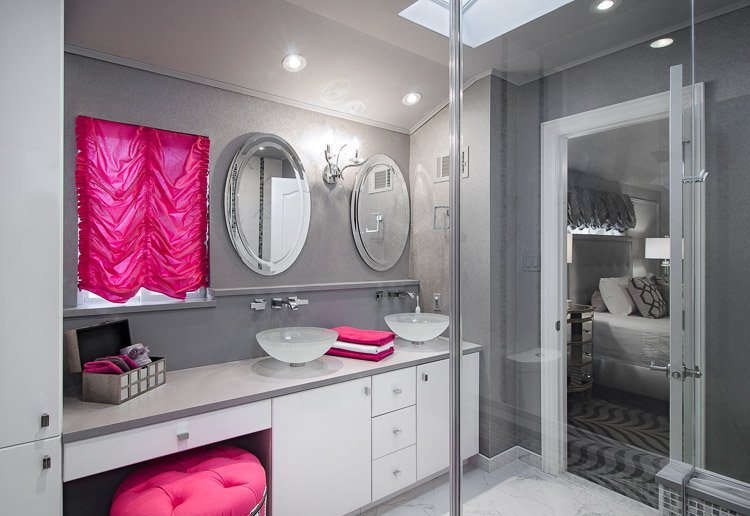 Grey bathroom with vanity with two vessel sinks and two mirrors with pops of pink