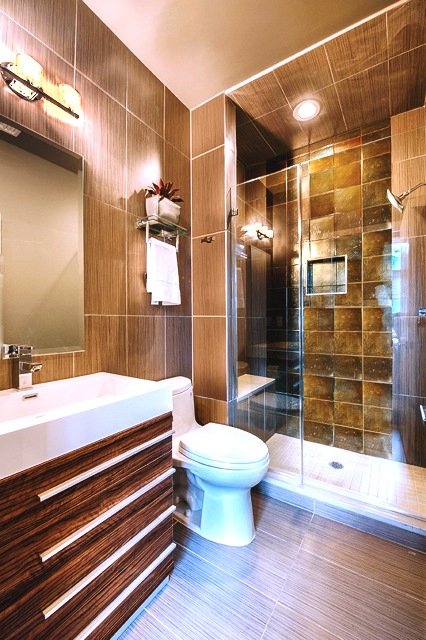 Brown bathroom with vanity, toilet and glass enclosed shower
