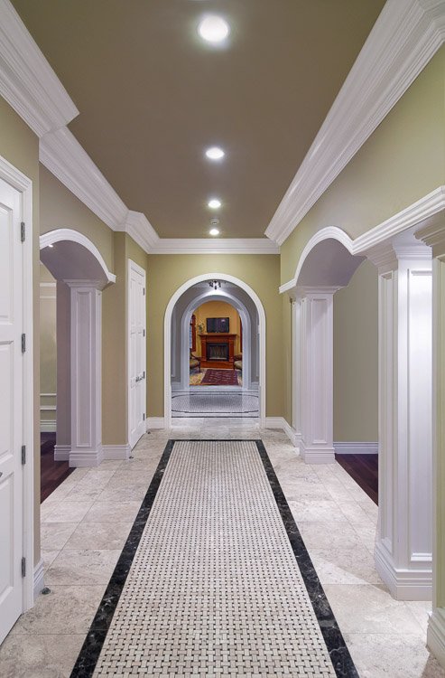 Hallway with stone floor, arches and openings into rooms off to each side