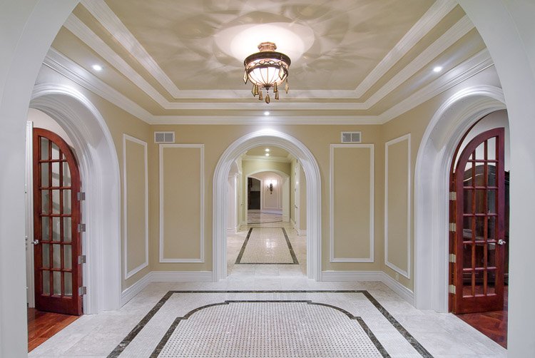 Ornate entryway with a lighting fixture, marble floor and hallway leading to various rooms