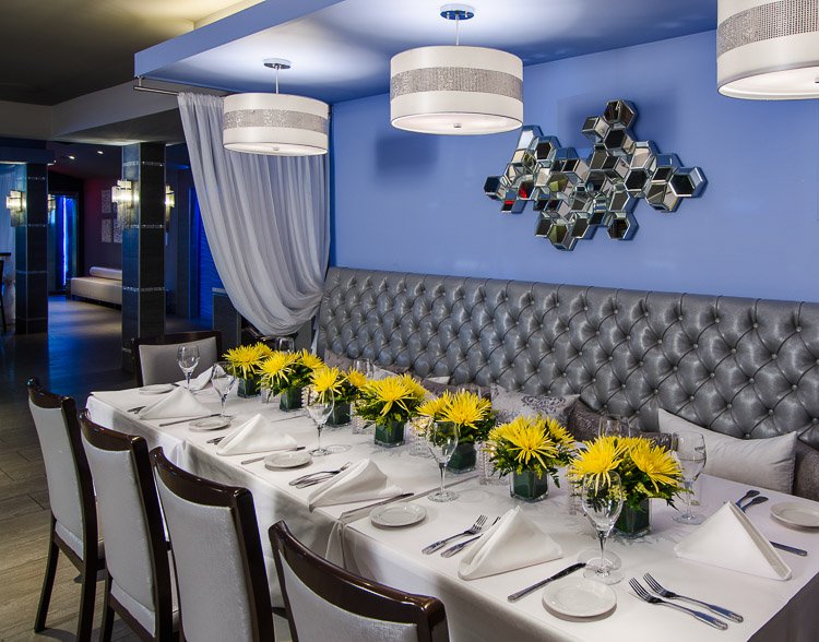 Marina Cafe table setting with chairs and banquette and yellow floral centerpieces