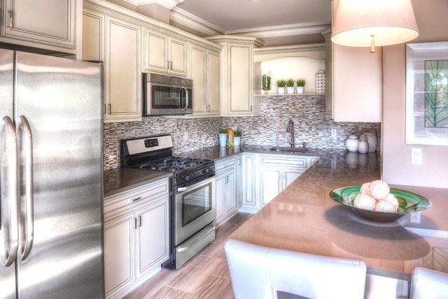 Kitchen with stainless steel appliances and white cabinets with a backsplash and island