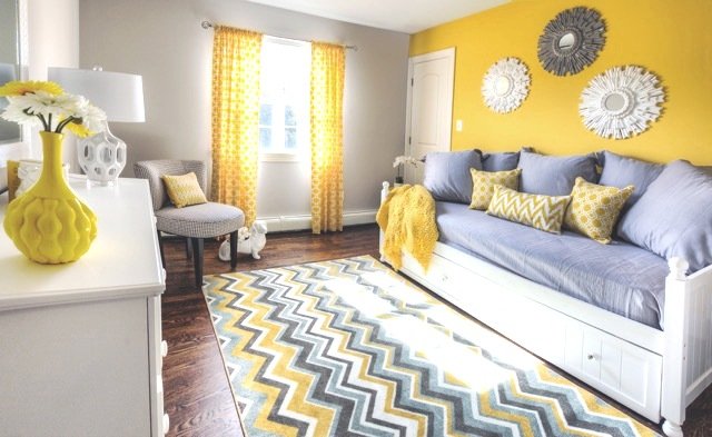 Day bed, chair, dresser and area rug in a room with a window and yellow walls and curtains