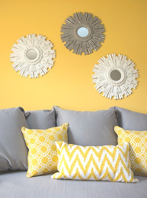 Grey couch with yellow and white throw pillows against a yellow wall