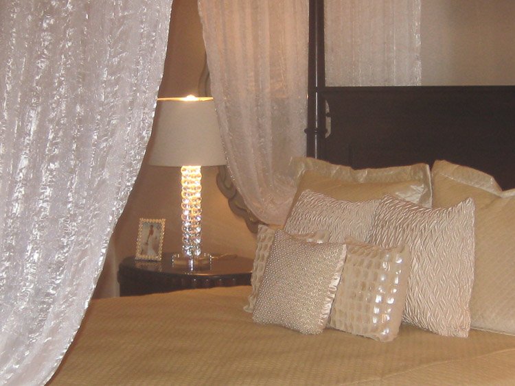 White linens on a bed with a view of a nighttable and lamp