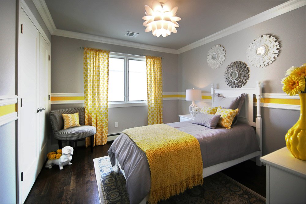 Grey and yellow bedroom with white bedframe, gray bedding and window