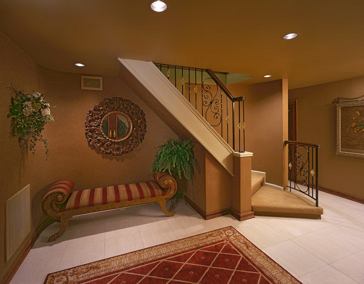 Foyer with a red and gold bench and area run and a stair case