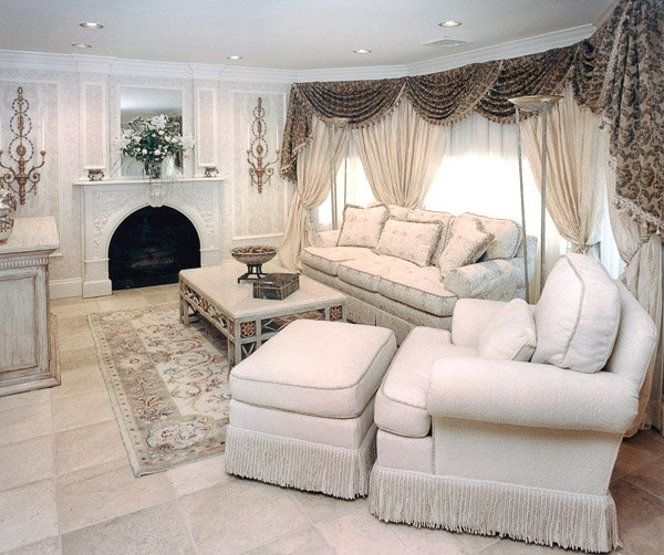 Living room with white sofa, chair, ottoman and coffee table with a fire place
