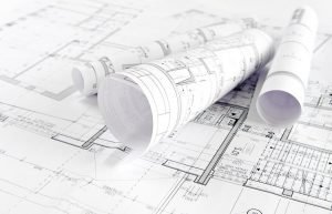 Why a Designer Should Review Your Architectural Plans three rolled up architectural plans on top of an open plan
