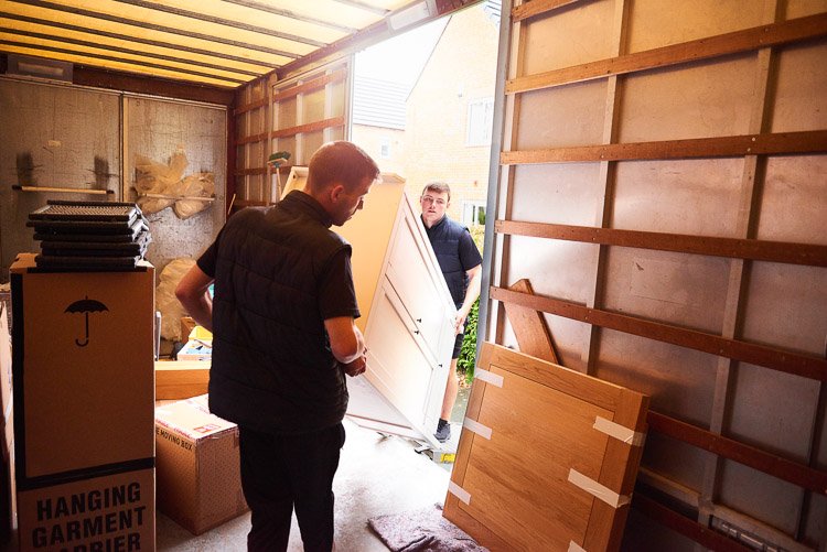 Two men moving furniture out of a moving truck
