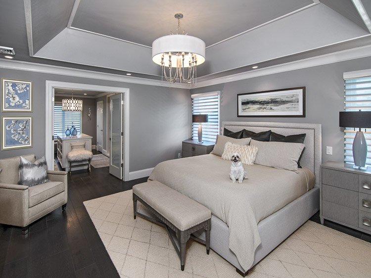 Master bedroom with bed, two nightstands, dog on bed, light fixture, carpet and bench